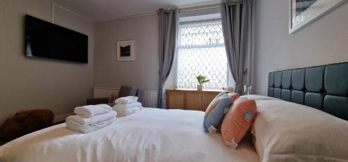 a bedroom with a bed with white sheets and towels at Woodland Family Apartment With Electric Car Point in Windermere