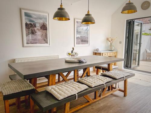 uma sala de jantar com uma mesa e bancos em The Light House em Camber