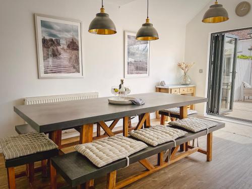 a dining room with a table and benches at The Light House in Camber