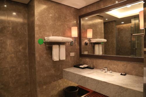 a bathroom with a sink and a mirror at Guangzhou ChangFeng Gloria Plaza Hotel in Zengcheng