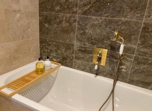 a bathroom with a bath tub with a faucet at 2 Bedroom Lux Apartment in Hendon- New Build in Colindale