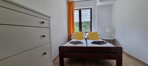 a bedroom with a bed with yellow pillows and a window at ŁOMIANKOWA DOLINA Wetlina 112 in Wetlina