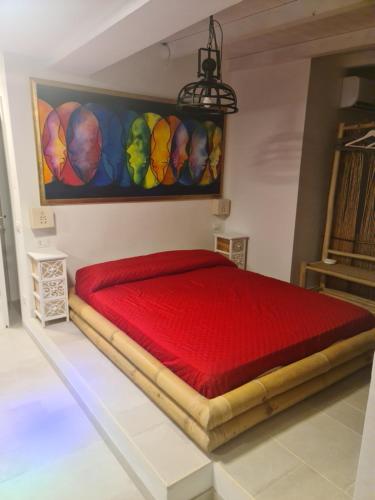 a bedroom with a red bed with a painting on the wall at Ulivi di Minerva - Boutique Holiday Home - SUPER SUITE & SPA POLLON - Ostuni - Fasano - Cisternino in Montalbano