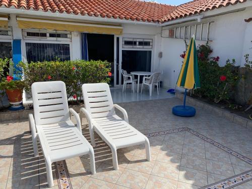 two white chairs and an umbrella on a patio at Casa Torres in San Bartolomé de Tirajana