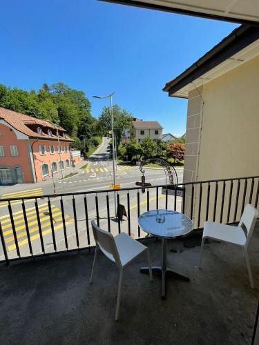 a table and chairs on a balcony with a view of a street at La Belle-Croix in Romont