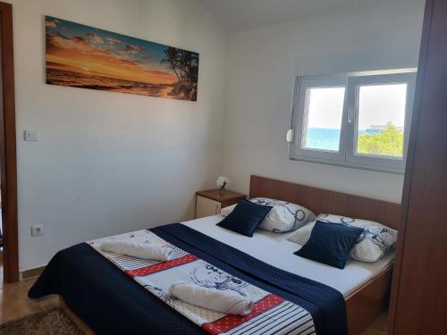Un dormitorio con una cama con almohadas azules y una ventana en Apartments Bralic, en Bibinje