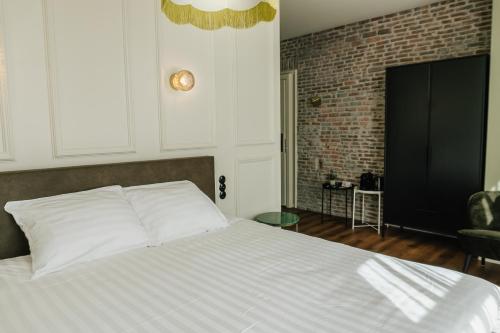 a bedroom with a white bed with a brick wall at In de Brouwerij in Leeuwarden