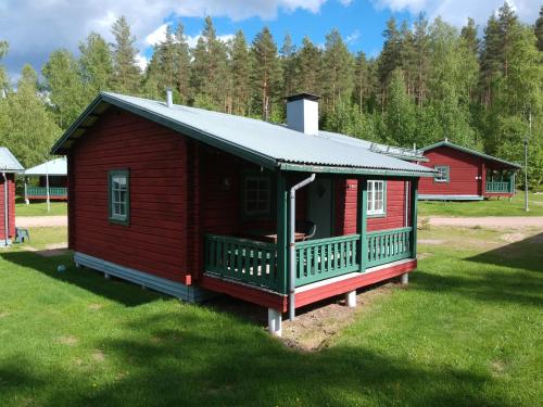 eine rote Hütte mit einer Veranda auf einem Rasenplatz in der Unterkunft Ekesberget Stugby Pippi Stuga in Ekshärad