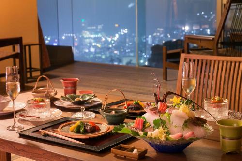 a table with plates of food and wine glasses at Watei Kazekomichi in Atami