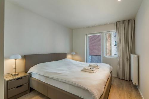 une chambre blanche avec un lit et une fenêtre dans l'établissement Rustig, comfortabel app op 50meter van het strand, à Coxyde