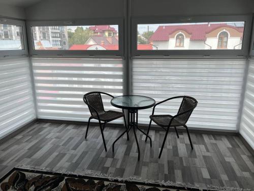 a table and two chairs in a room with two windows at Апартаменти в центрі Трускавця in Truskavets