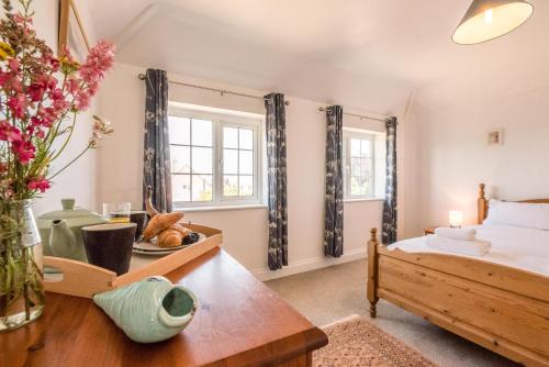 Un dormitorio con una cama y una mesa con un jarrón de flores en Culver House en Aldeburgh