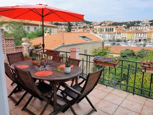 a table and chairs on a balcony with an umbrella at Villa du Port in Port-Vendres