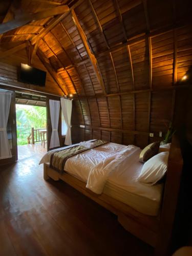 a bed in a room with a wooden ceiling at Ita House in Tegalalang