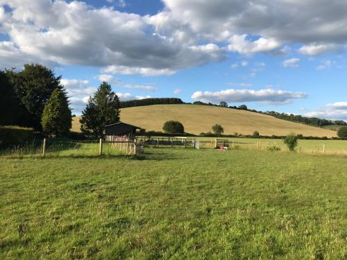 a field of green grass with a barn on a hill at Charlton End - Goodwood Events in Chichester