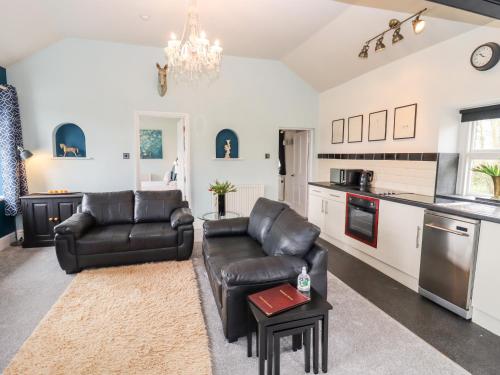 sala de estar con 2 sofás de cuero y cocina en The Stable, en Lydney