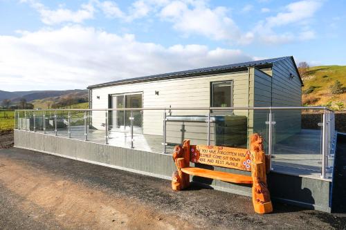 a tiny house with a bench in front of it at Castlehill cabin with a hot tub in Peebles