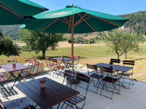 a group of tables and chairs under a green umbrella at Römercastell Wirtshaus & Hotel in Böhming