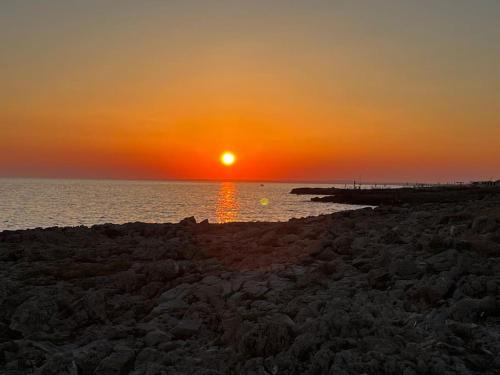a sunset over the ocean with a rocky beach at Casa Matilde a pochi passi dal mare in Torre Squillace