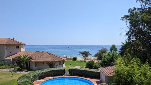 - une piscine en face d'une maison et de l'océan dans l'établissement Cala di sognu, à San-Nicolao