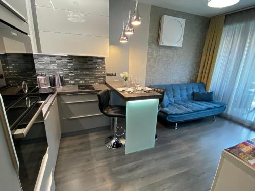 a kitchen with a table and a blue couch at Noir Silvery Apartman in Szeged