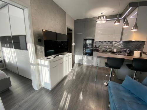 a large kitchen with white cabinets and a blue couch at Noir Silvery Apartman in Szeged