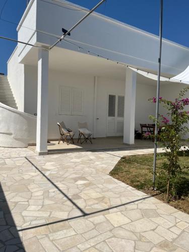 a patio with a white building and a white umbrella at Casa Matilde a pochi passi dal mare in Torre Squillace