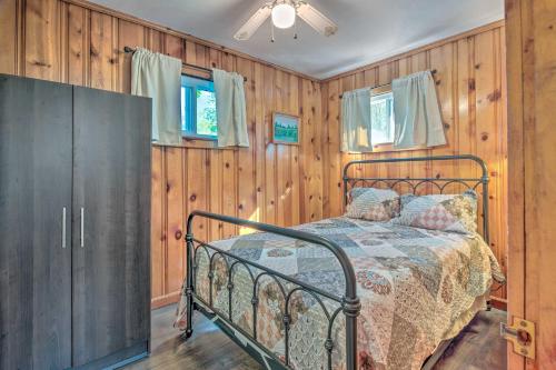 Cozy Newton Lake Cottage with View of the Lake! في Carbondale: غرفة نوم بها سرير في غرفة بجدران خشبية