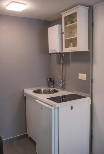 a small kitchen with white cabinets and a sink at Studio Gallery in Mostar