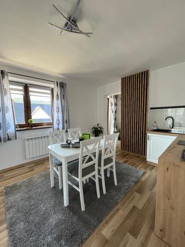 uma sala de jantar branca com uma mesa e cadeiras brancas em Apartamenty Cichy Kącik em Poronin