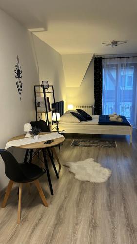 a bedroom with a bed and a table and a chair at Apartamenty Cichy Kącik in Poronin
