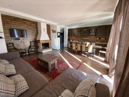 a living room with a couch and a table and a kitchen at Mountain Cricket Chalets and Apartments Gudauri in Gudauri