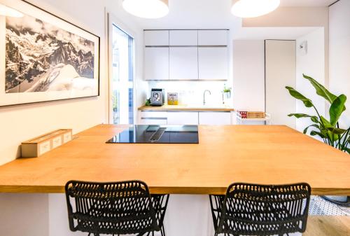 a large wooden table in a kitchen with two chairs at L'Olympique: appartement cosy, vue canal grande terrasse et parking in Vaires-sur-Marne
