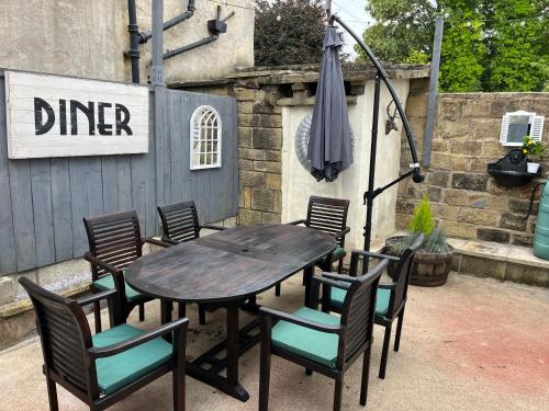 a wooden table with chairs and an umbrella at Redfearn Cottage in Apperley Bridge