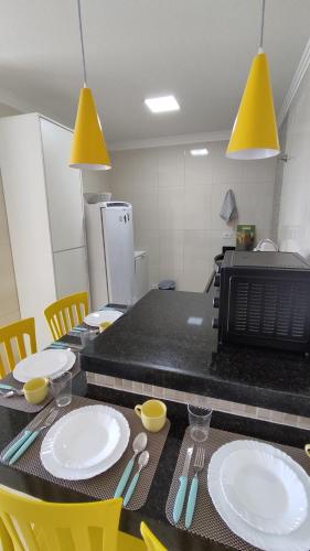 una cocina con una mesa con platos blancos y sillas amarillas en Flat Bella Maré - Arradi, en Maragogi