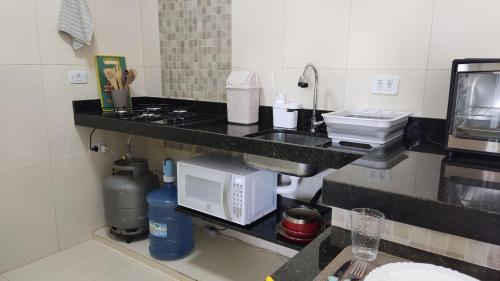 a kitchen with a counter with a sink and a microwave at Flat Bella Maré - Arradi in Maragogi