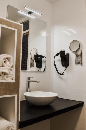een badkamer met een witte wastafel en een spiegel bij Hotel ten Cate Emmen in Emmen