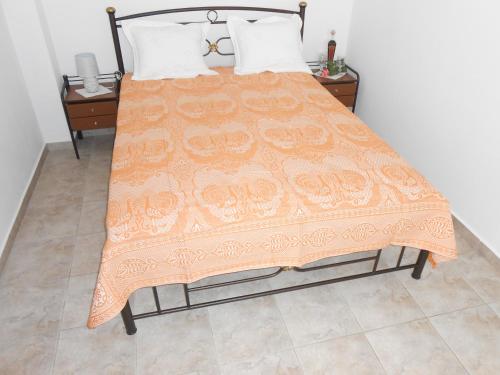 a bed with an orange blanket on top of it at Chrysolithos Kerami Apartments in Khalkíon