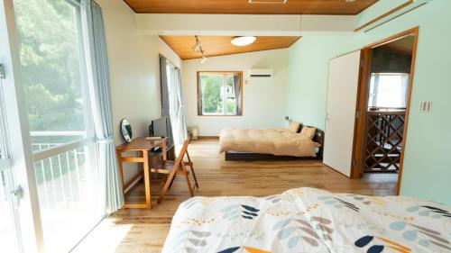 Schlafzimmer mit einem Bett, einem Schreibtisch und einem Fenster in der Unterkunft ヴィラ バルゴ in Inbu