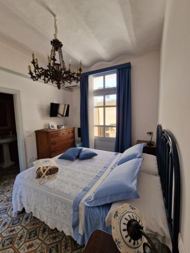 a bedroom with a bed with blue pillows and a window at Ngonia Bay Boutique Hotel in Milazzo