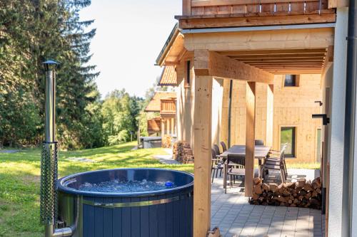 una bañera de hidromasaje en el patio trasero de una casa en Englmar Chalets by ALPS RESORTS, en Sankt Englmar