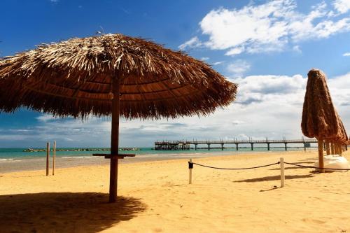 a straw umbrella on a beach with a pier at Design Sea Apartment -BOHO SUITE- Abruzzo in Francavilla al Mare