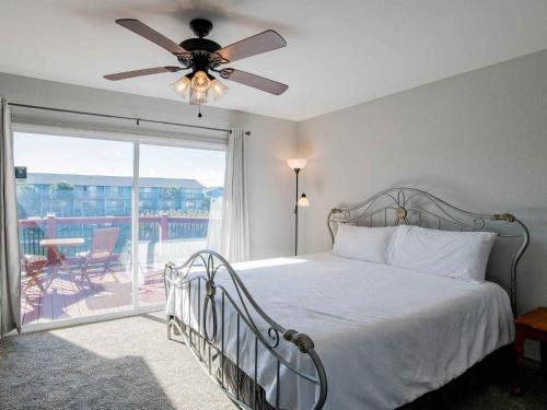 um quarto com uma cama, uma ventoinha de tecto e uma varanda em Moonlight Beach Villa em Pensacola Beach