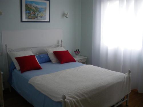 1 dormitorio con 1 cama con 2 almohadas rojas en Gîte CLIMATISE les althéas, en Lanquais