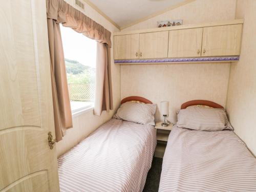 two beds in a small room with a window at Grange Caravan in Llangollen