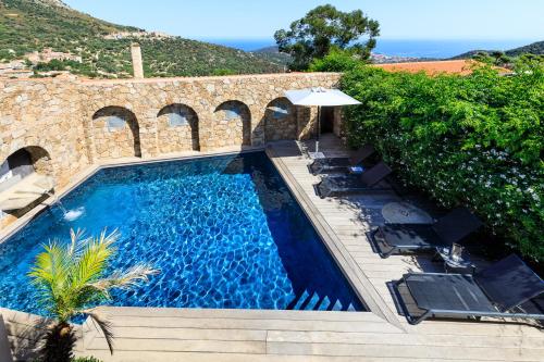 une piscine avec des chaises et un parasol dans l'établissement U CASALE, à Santa-Reparata-di-Balagna