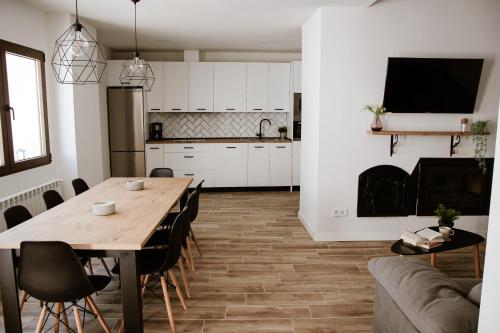 a kitchen and living room with a wooden table and chairs at El Retiro de la Adrada AVILA in La Adrada