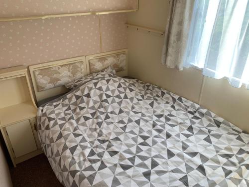 een slaapkamer met een bed met een zwart-wit dekbed bij stacaravan Mientje in Hantum