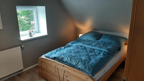 a bed with a blue comforter and a window at Hof an der Semkenfahrt - Adele in Worpswede