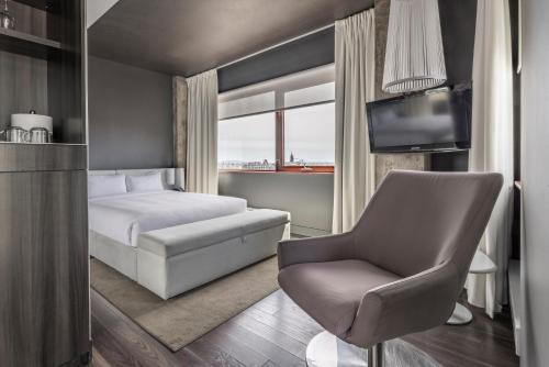 a bedroom with a bed and a chair and a television at Hotel Zero 1 Montreal in Montréal